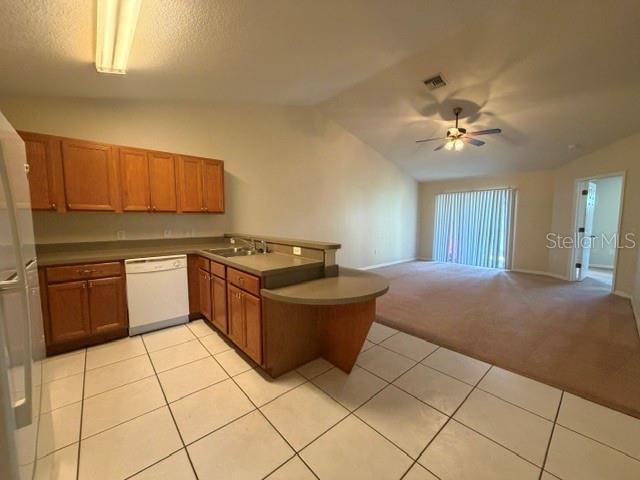 A kitchen with wood cabinets and tile flooring opens to a carpeted living area — 31-33 E ST LOUIS AVENUE, EUSTIS, FL