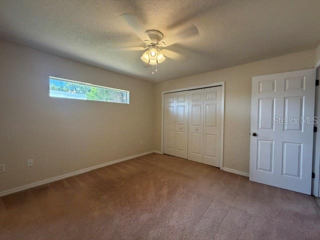 A bedroom features beige carpet, a ceiling fan, a horizontal window, and white closet doors — 31-33 E ST LOUIS AVENUE, EUSTIS, FL