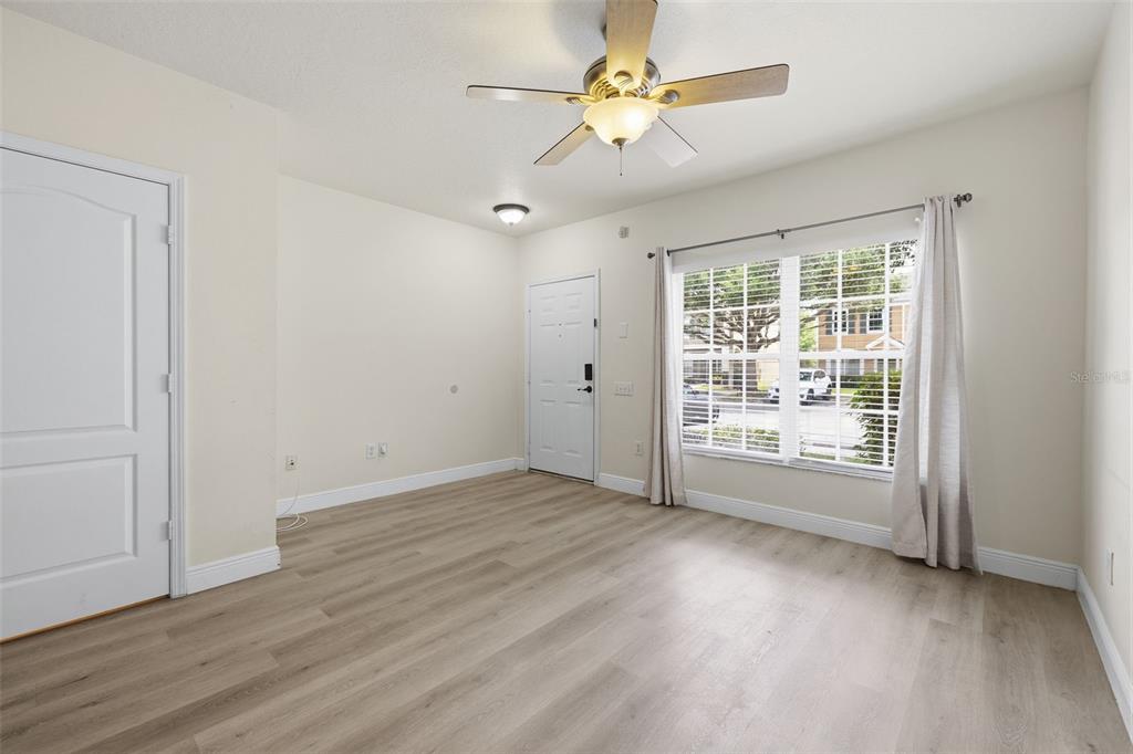 An empty room features light wood-look flooring, a ceiling fan, and a window with curtains — 1141 KENNEWICK COURT, WESLEY CHAPEL, FL