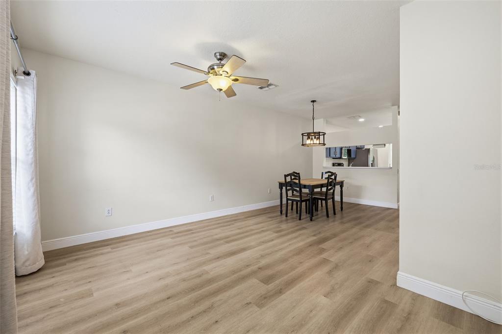 A dining area with wood-look flooring, a ceiling fan, and a light fixture over a table — 1141 KENNEWICK COURT, WESLEY CHAPEL, FL