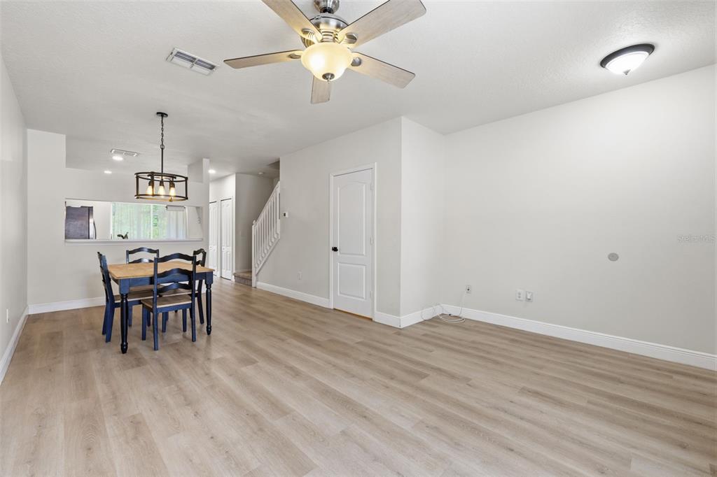 An open-concept living and dining area features light wood-look flooring and a ceiling fan — 1141 KENNEWICK COURT, WESLEY CHAPEL, FL