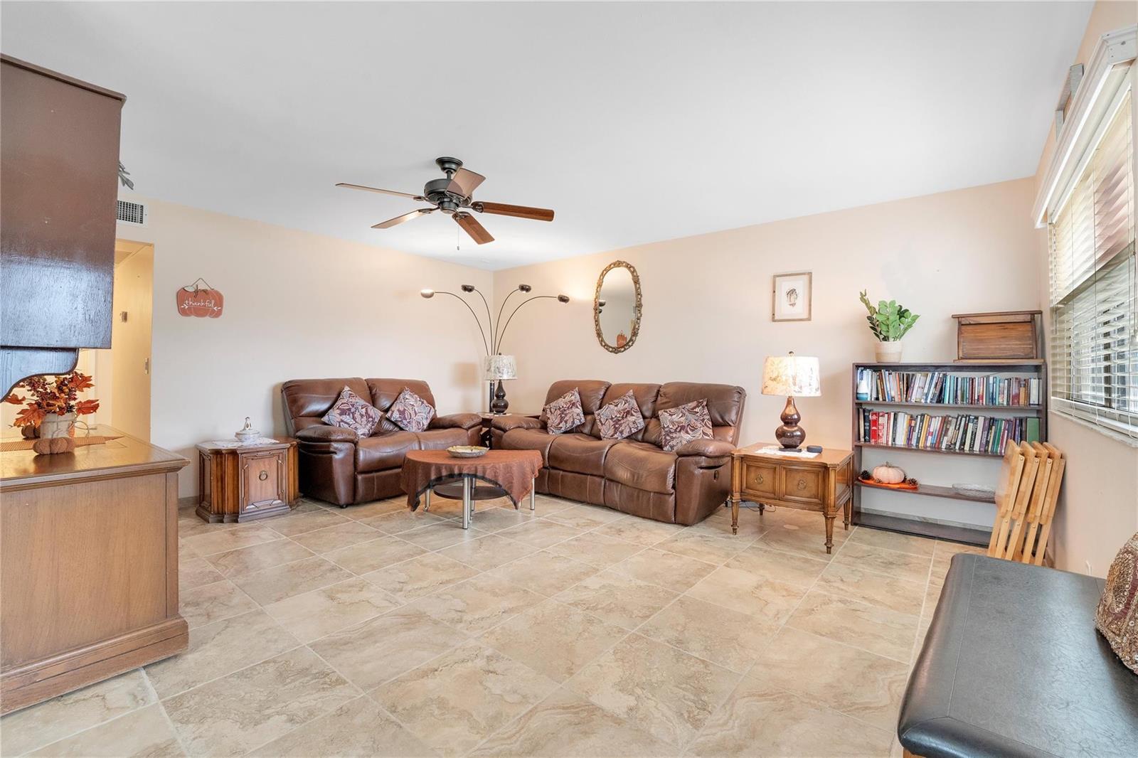 A living room with tile flooring, two brown leather sofas, and a wooden bookshelf — 201 Valencia I, Delray Beach FL 33446, DELRAY BEACH, FL