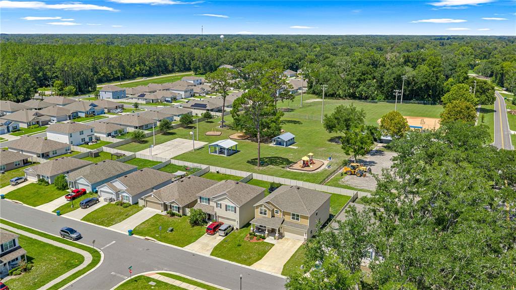 An aerial view shows a suburban neighborhood with houses bordering a park containing a playground — 826 NW 244TH DRIVE, NEWBERRY, FL