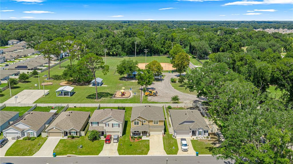An aerial view shows a row of suburban houses bordering a park with a baseball field — 826 NW 244TH DRIVE, NEWBERRY, FL