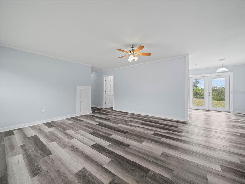 A living room features light blue walls, wood-look plank flooring, and a ceiling fan — 5926 VAN SIMMONS ROAD, WAUCHULA, FL