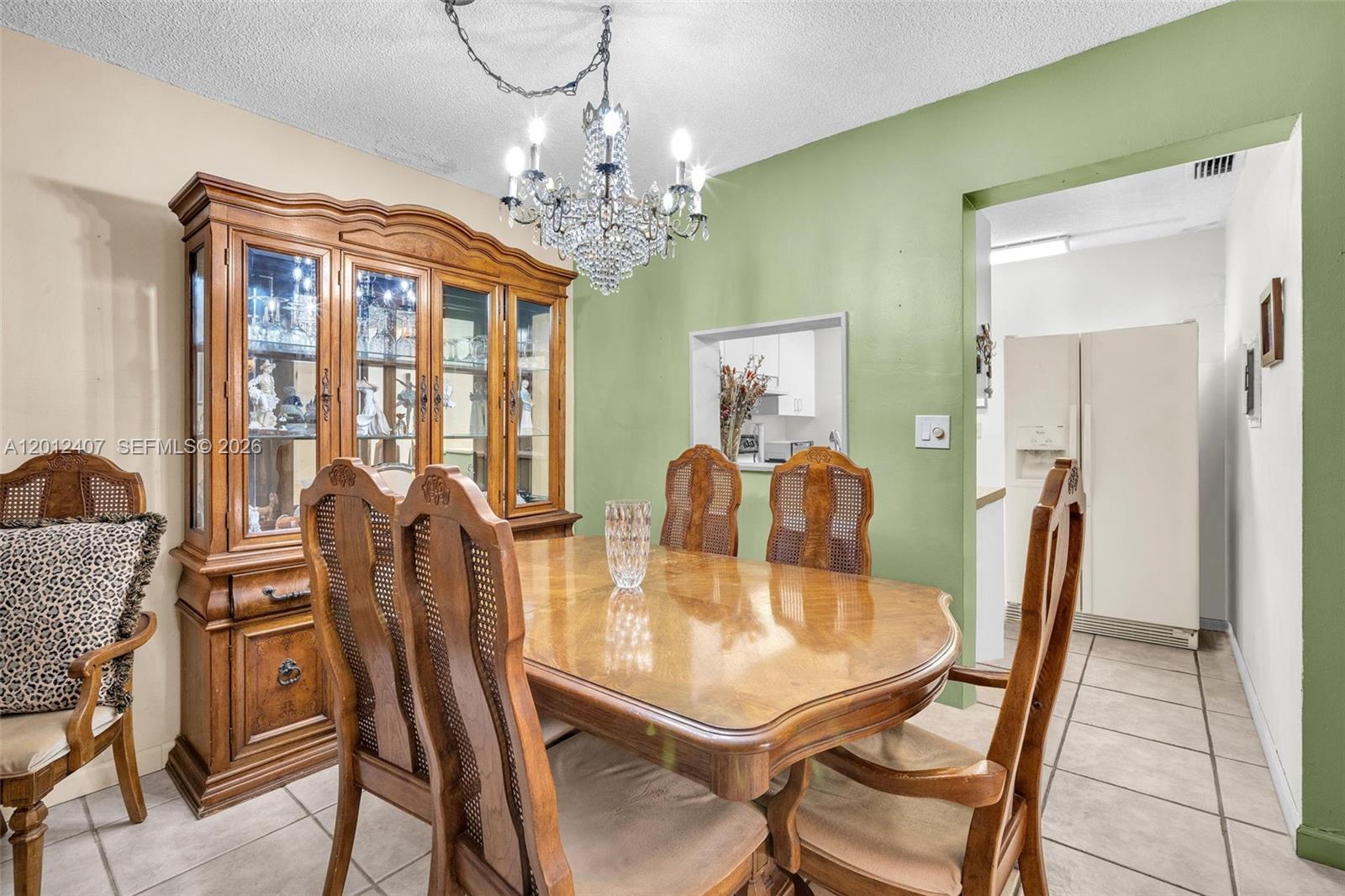 A dining room features a wooden hutch, a crystal chandelier, and a table with chairs — 16901 NE 13th Ave # 303, Miami FL 33162, MIAMI, FL