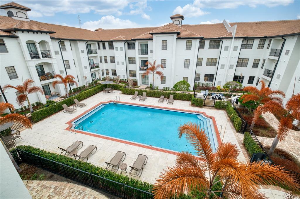 An elevated view of a rectangular swimming pool surrounded by lounge chairs and apartment buildings — 5550 E MICHIGAN STREET UNIT 3306, ORLANDO, FL