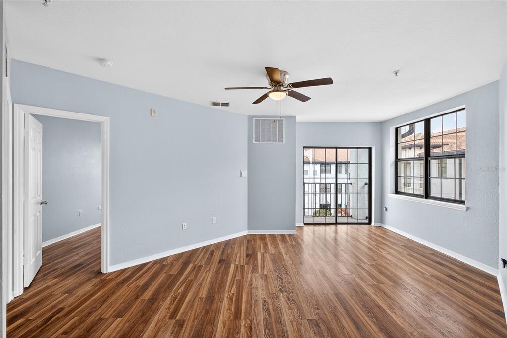 An empty room with light blue walls, wood-look flooring, a ceiling fan, and a balcony door — 5550 E MICHIGAN STREET UNIT 3306, ORLANDO, FL