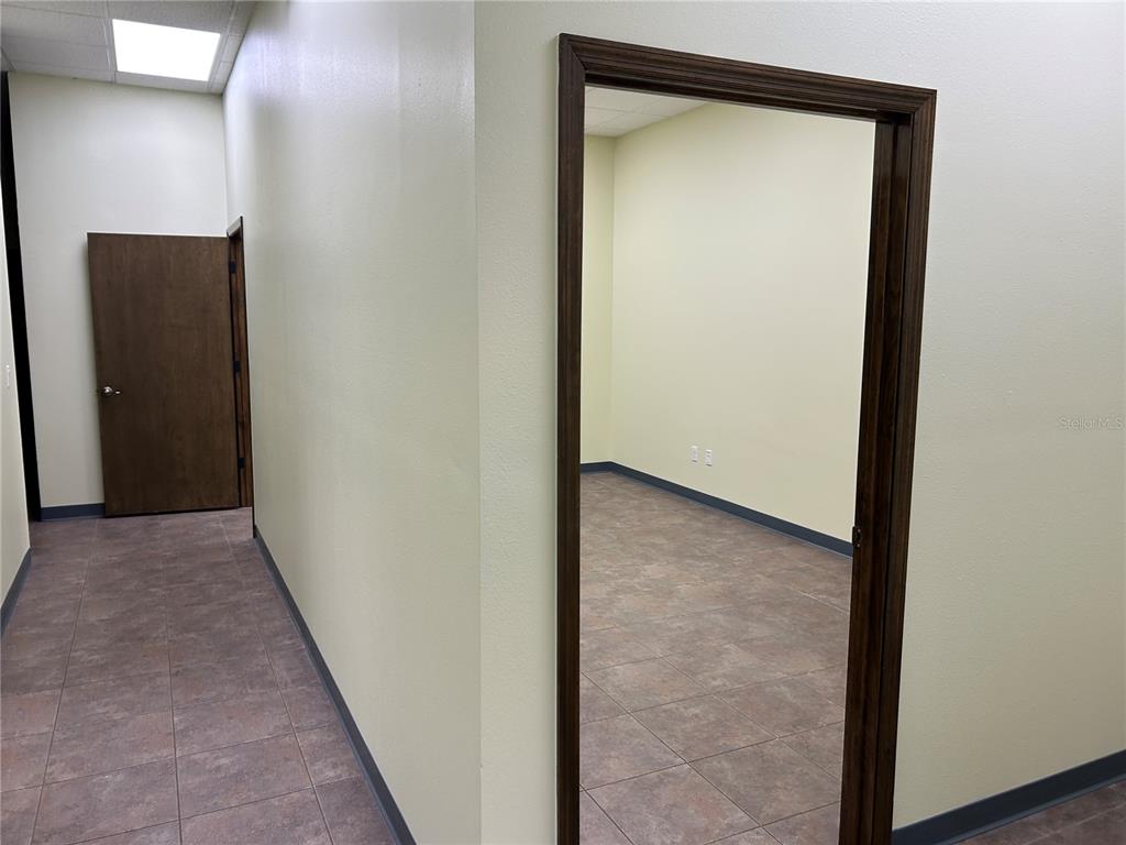 An interior view shows a hallway leading to a closed door and an open office — 4426 NE 83RD ROAD UNIT 4426, WILDWOOD, FL