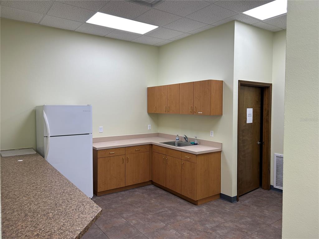 A breakroom features light-colored walls, wood cabinets, a sink, and a white refrigerator — 4426 NE 83RD ROAD UNIT 4426, WILDWOOD, FL