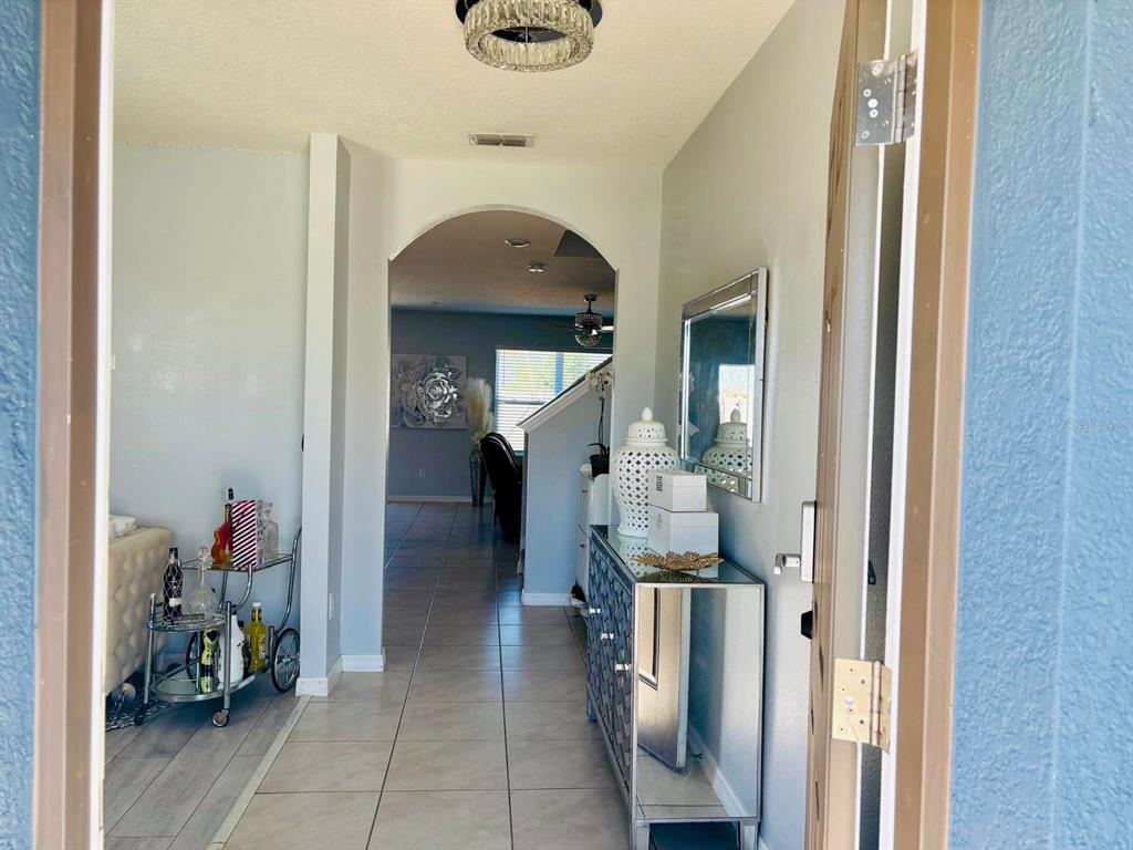 A view from an entryway into a home with tiled floors, an arched doorway, and furniture — 5837 ARLINGTON RIVER DRIVE, LAKELAND, FL