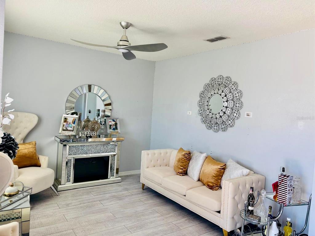 A living room features a mirrored fireplace, a cream sofa, and a decorative wall mirror — 5837 ARLINGTON RIVER DRIVE, LAKELAND, FL
