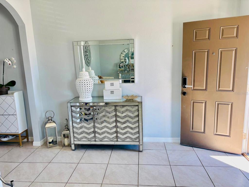 An entryway features a mirrored console table, a wall mirror, and a brown front door — 5837 ARLINGTON RIVER DRIVE, LAKELAND, FL