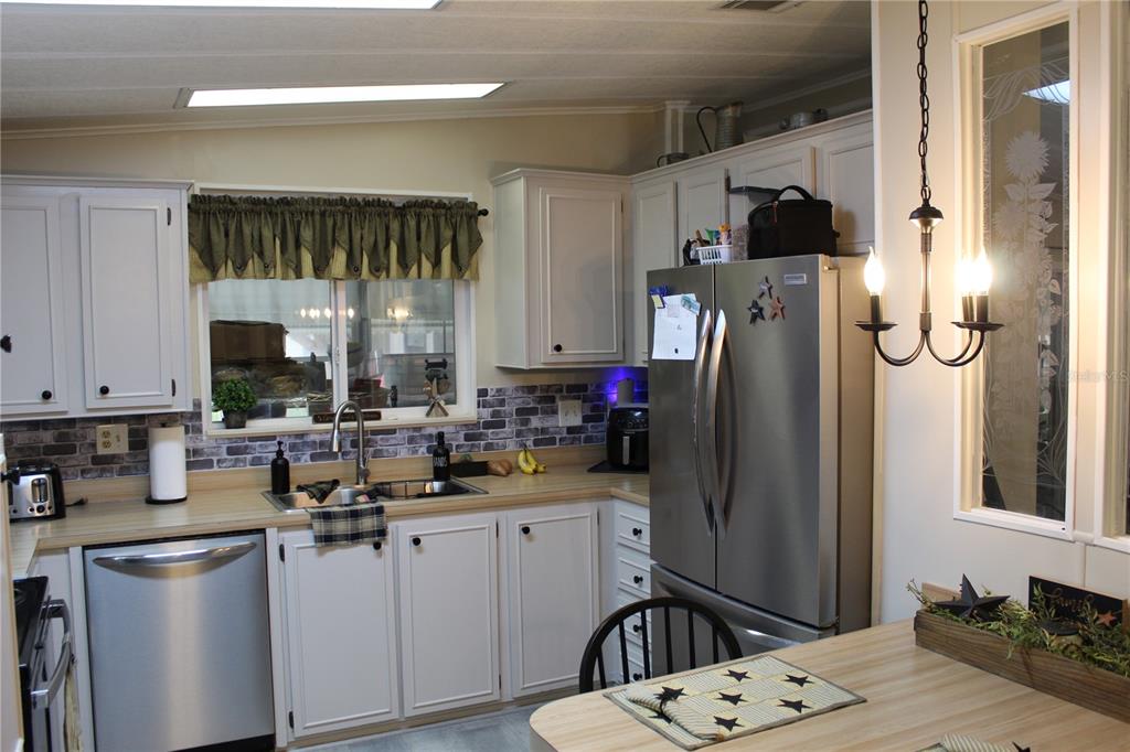 A kitchen features white cabinets, stainless steel appliances, a brick-patterned backsplash, and a wooden countertop — 6369 ELMWOOD AVENUE, LAKE WALES, FL