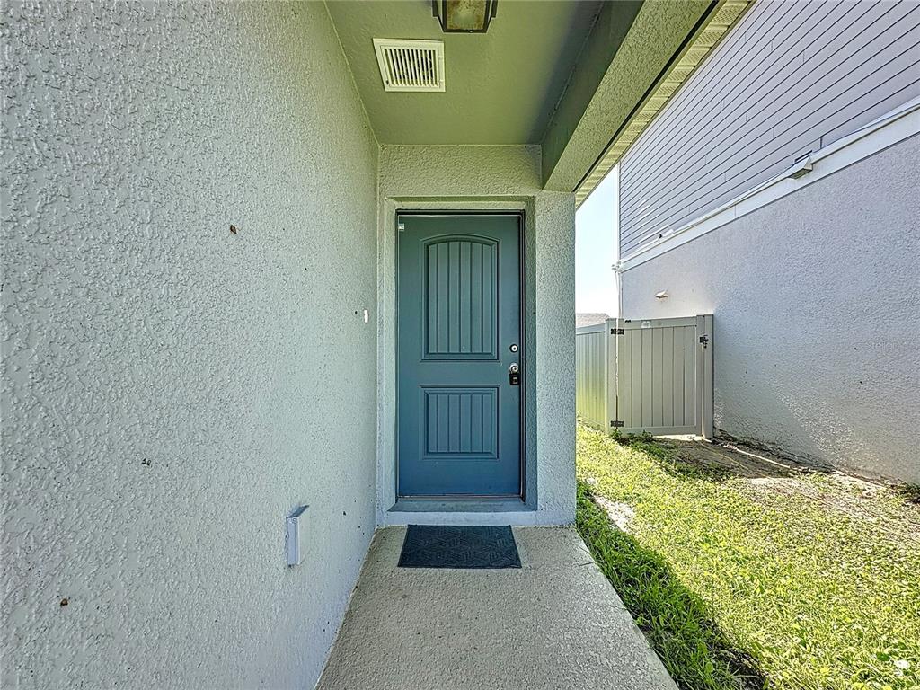 A teal front door is set within a covered entryway next to a side yard — 707 SCRUB OAK HAMMOCK ROAD, DAVENPORT, FL