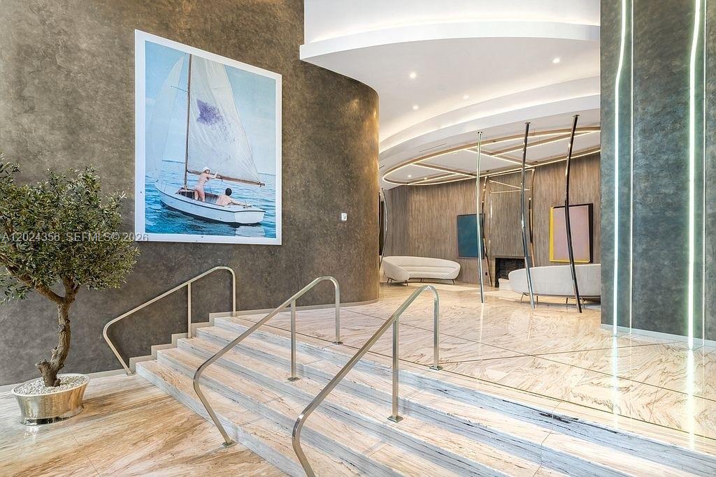 A modern lobby features marble stairs, a large sailboat painting, and curved accent walls — 1000 Brickell Plz # 2108, Miami FL 33131, MIAMI, FL