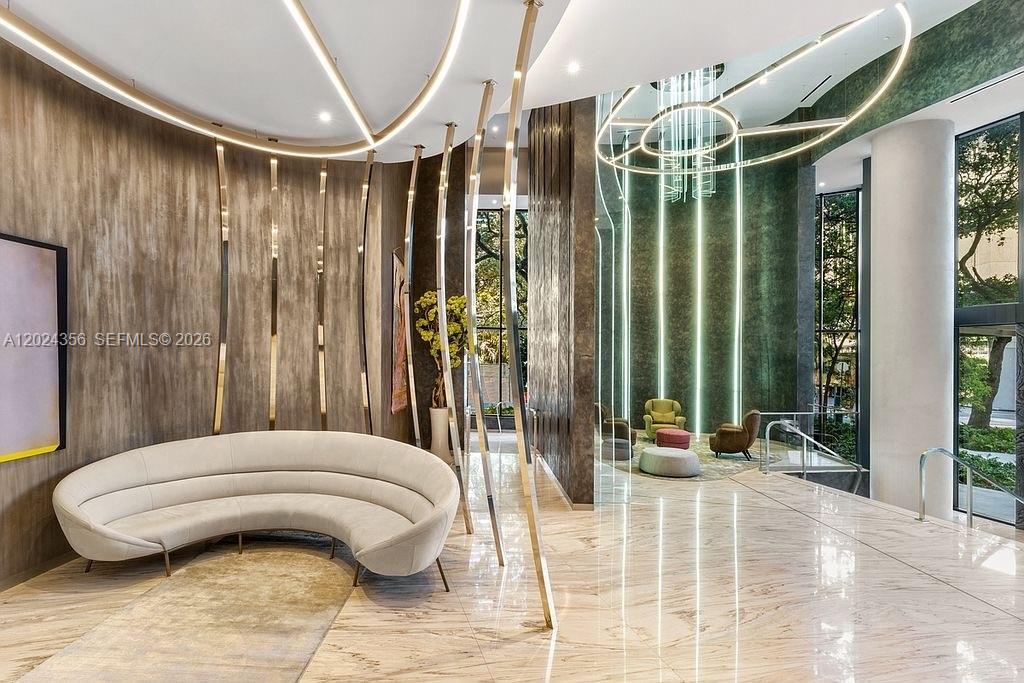 A modern lobby features a curved sofa, marble floors, and vertical metallic accent lighting — 1000 Brickell Plz # 2108, Miami FL 33131, MIAMI, FL