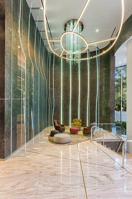 A modern lobby features marble floors, a large circular chandelier, and vertical accent lighting — 1000 Brickell Plz # 2108, Miami FL 33131, MIAMI, FL