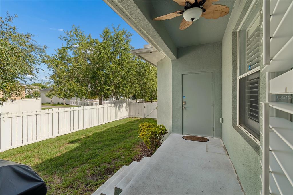 A covered concrete patio features a ceiling fan and a door leading to a fenced yard — 10207 PORCH STREET, NEW PORT RICHEY, FL