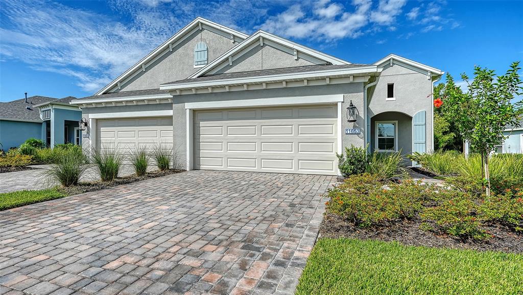 A single-story house with a paved driveway, two-car garage, and light-colored stucco exterior — 11653 GREAT BROOK LANE, PARRISH, FL