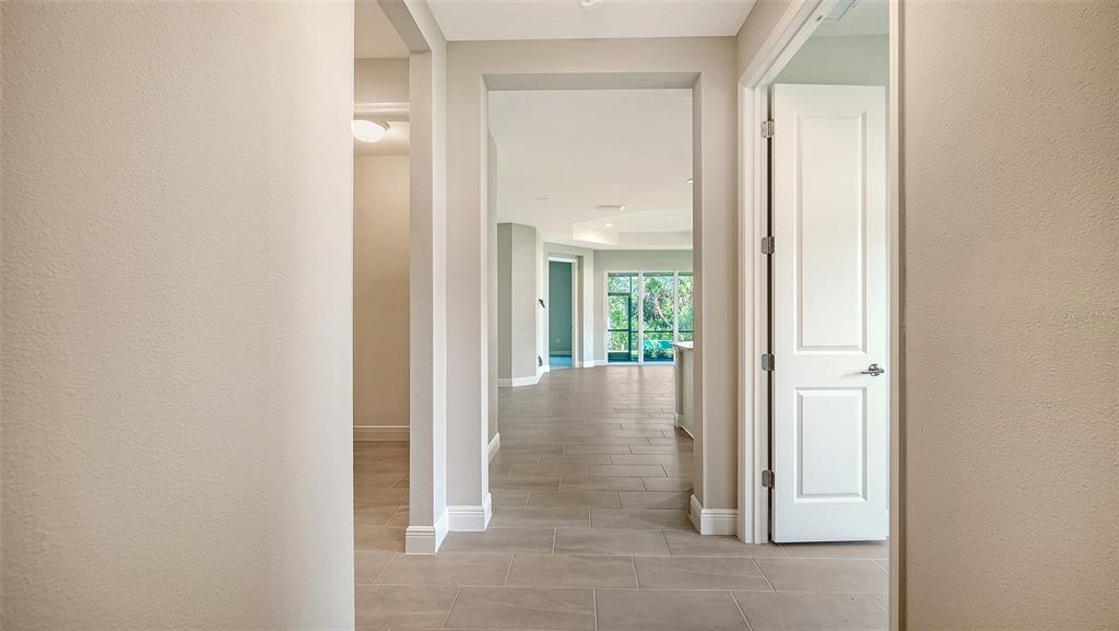 A view through a hallway with tile flooring into an open living area with windows — 11653 GREAT BROOK LANE, PARRISH, FL