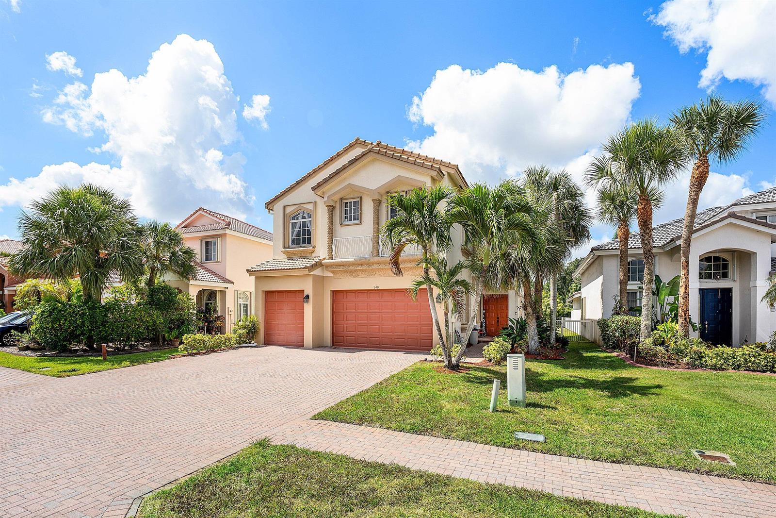A two-story suburban house features a brick driveway, two garage doors, and palm trees — 140 Bellezza Terrace, Royal Palm Beach FL 33411, ROYAL PALM BEACH, FL