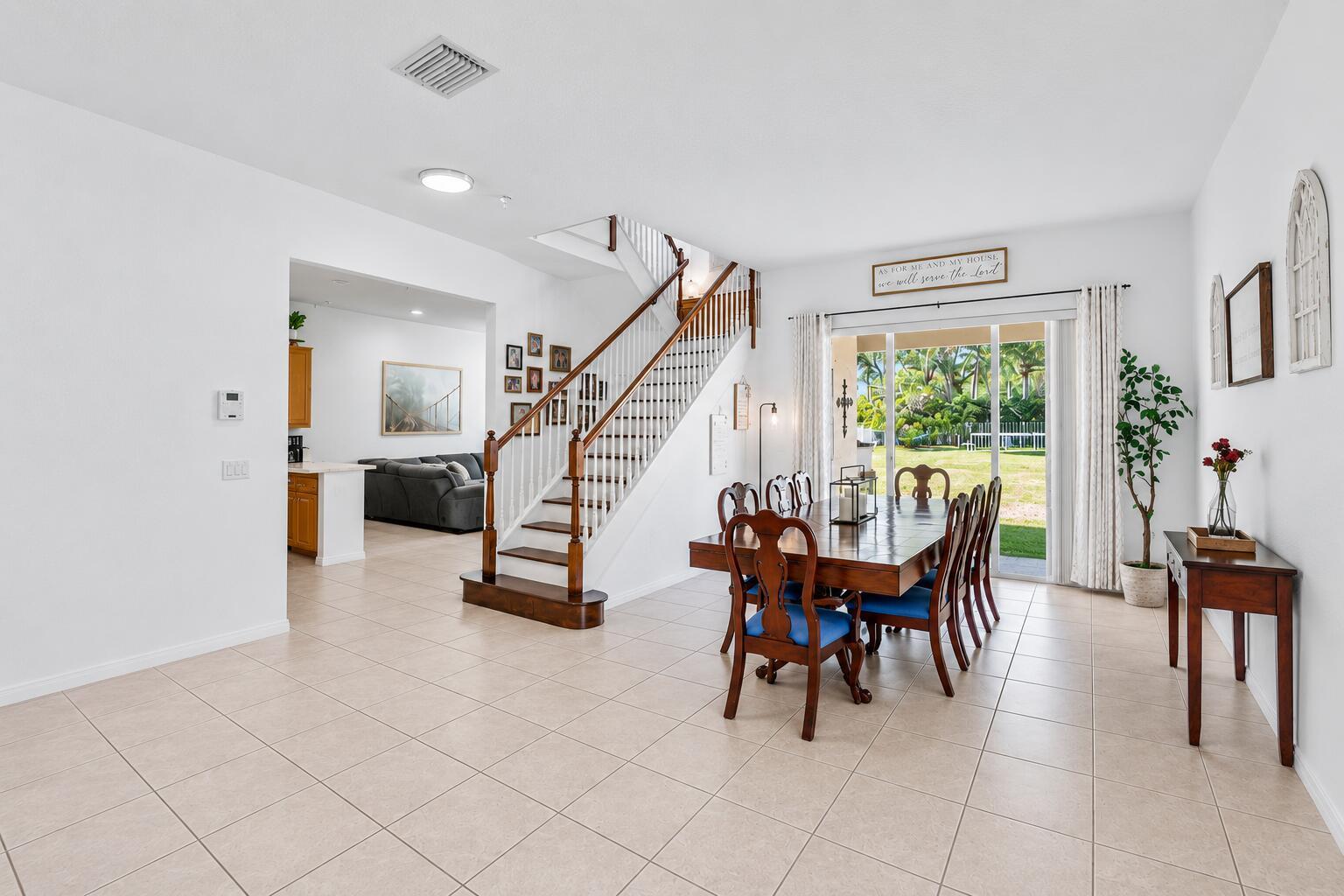 A dining area with a wooden table and stairs leading to an upper floor — 140 Bellezza Terrace, Royal Palm Beach FL 33411, ROYAL PALM BEACH, FL