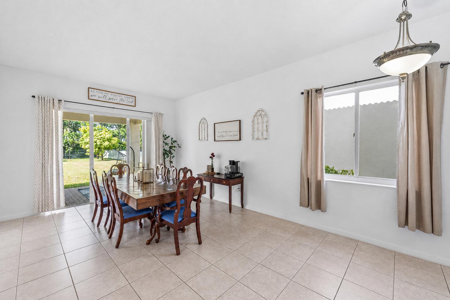 A dining room with tile floors, a wooden table, and a sliding glass door to a yard — 140 Bellezza Terrace, Royal Palm Beach FL 33411, ROYAL PALM BEACH, FL