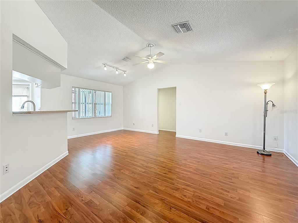 An empty living room features wood-look flooring, white walls, a ceiling fan, and recessed lighting — 3845 ERIN BROOK DRIVE, NEW PORT RICHEY, FL