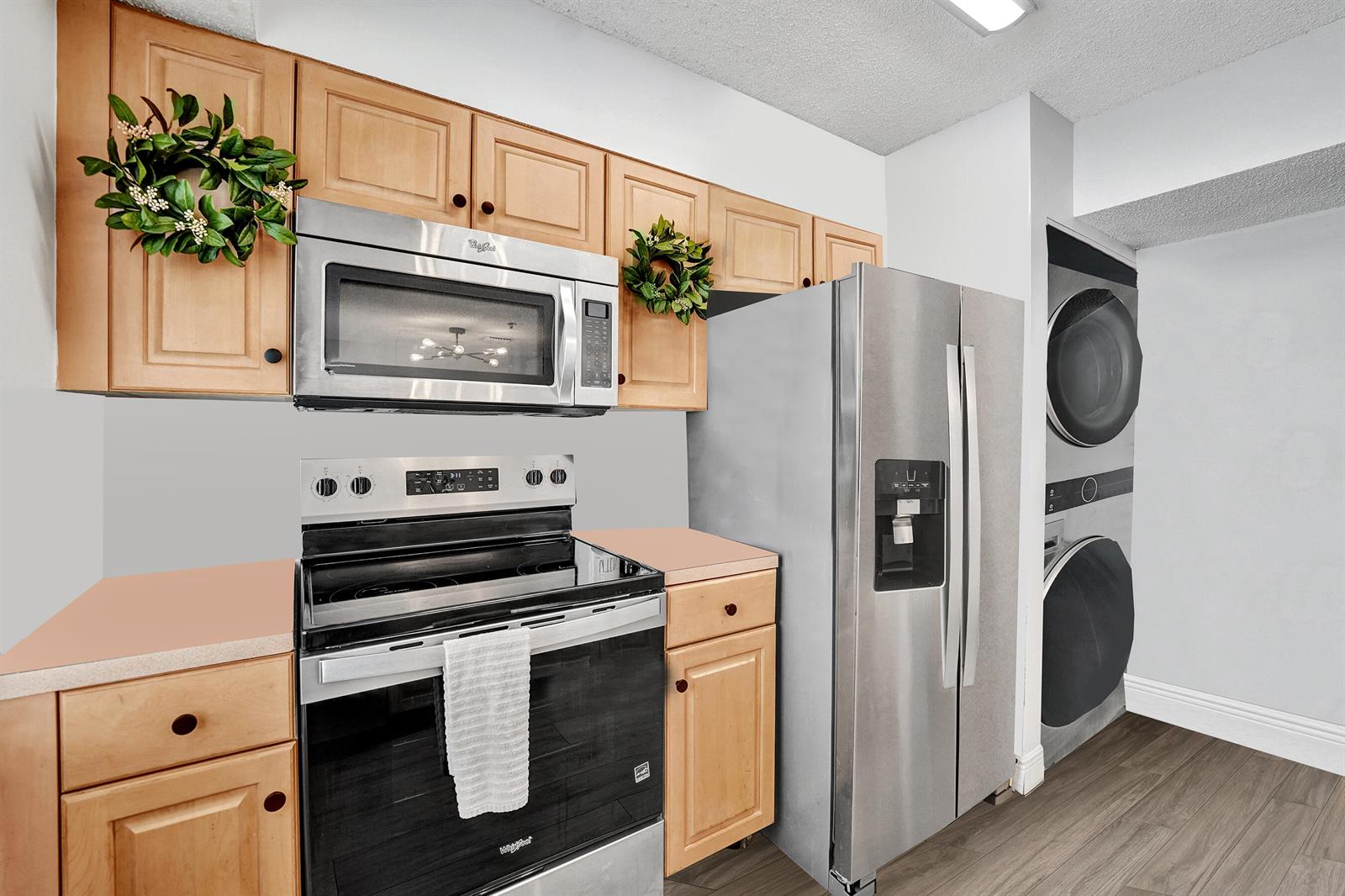 A kitchen features light wood cabinets, stainless steel appliances, and a stacked washer and dryer — 173 Riviera Circle, Weston FL 33326, WESTON, FL
