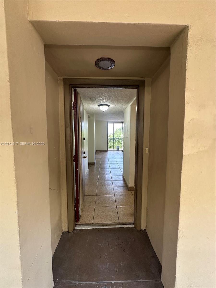A view through an open doorway reveals a tiled hallway leading to a balcony — 8635 NW 8th St # 320, Miami FL 33126, MIAMI, FL