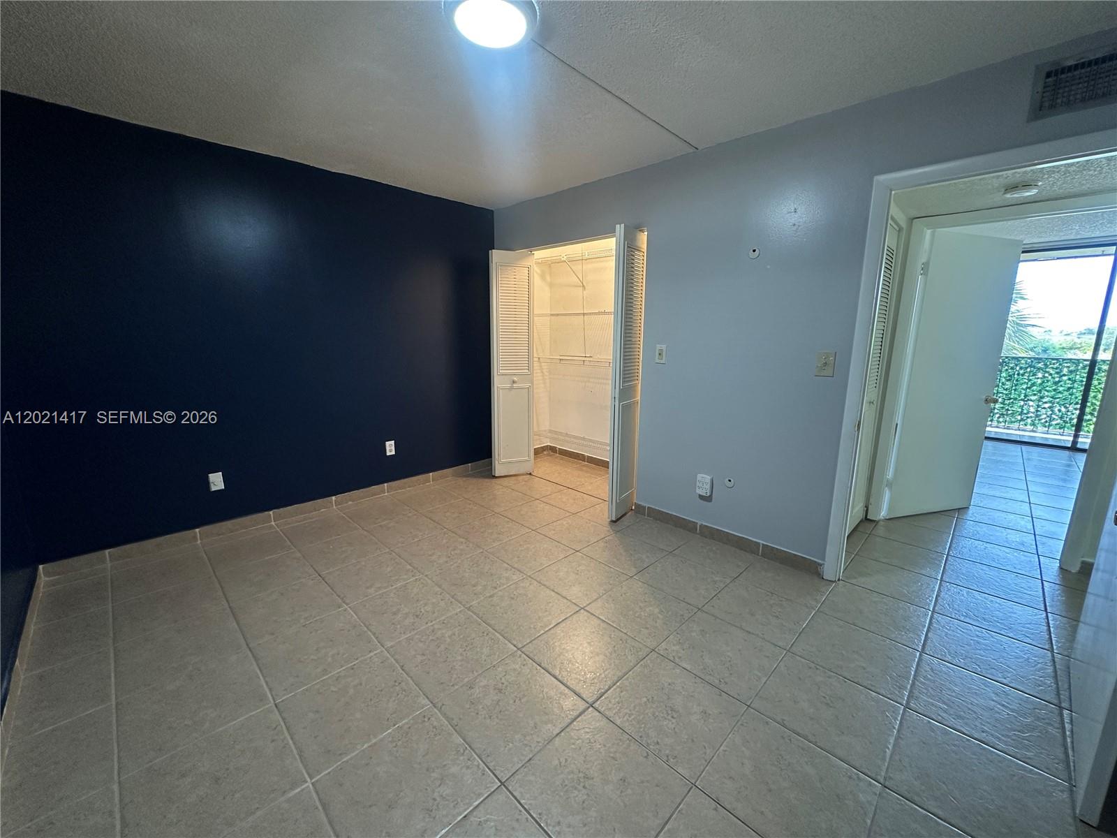 A room with light-colored tile flooring, a dark blue accent wall, and an open closet — 8635 NW 8th St # 320, Miami FL 33126, MIAMI, FL