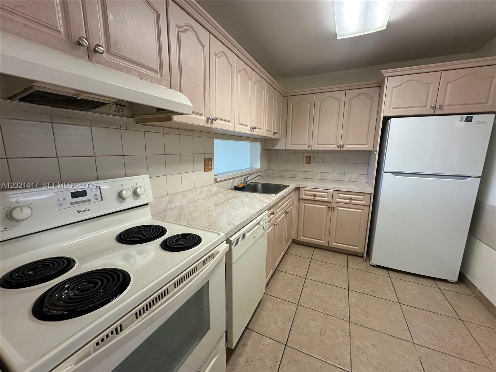 A kitchen features light-colored cabinets, white appliances, a tiled backsplash, and beige floor tiles — 8635 NW 8th St # 320, Miami FL 33126, MIAMI, FL