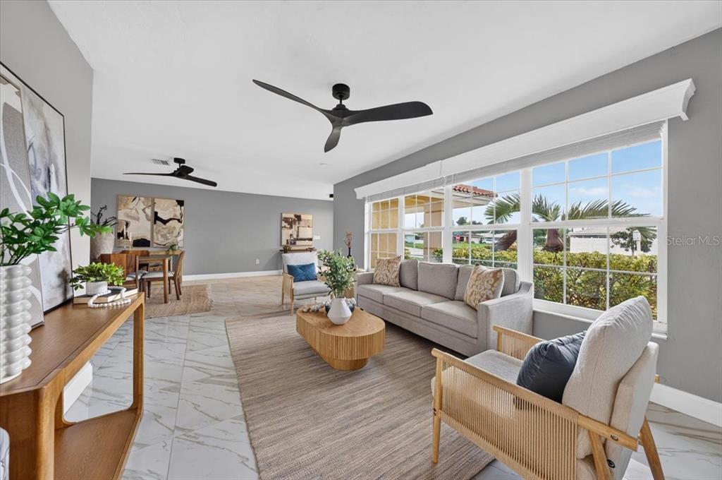 A living room features gray walls, a light-colored sofa, two ceiling fans, and large windows — 100 MATISSE CIRCLE W, NOKOMIS, FL