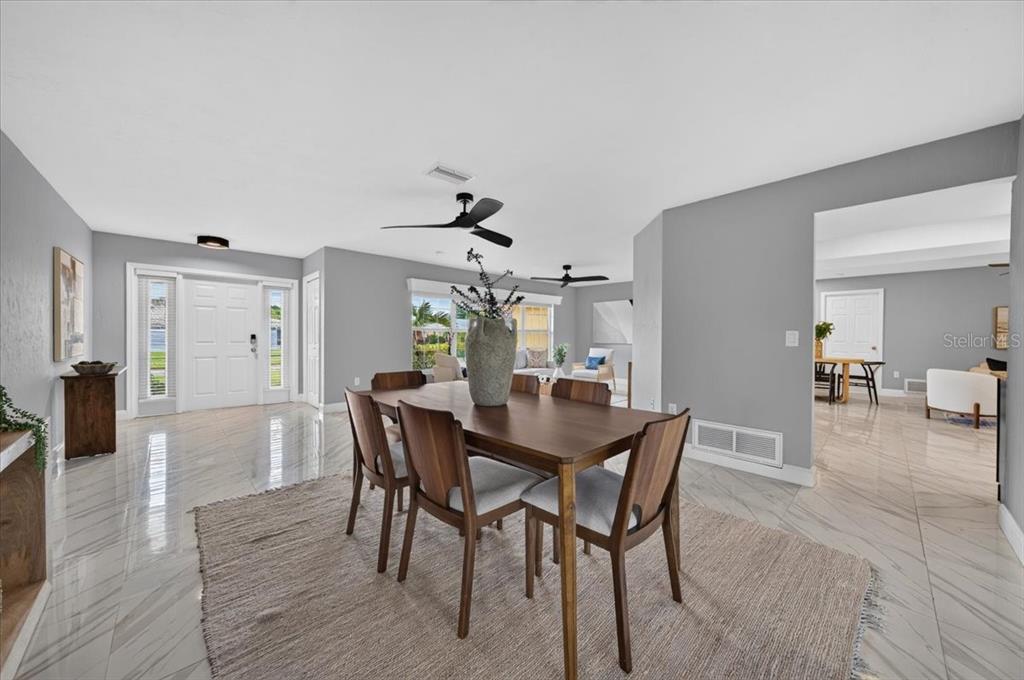 A dining area with a wooden table and chairs sits on a rug over tile floors — 100 MATISSE CIRCLE W, NOKOMIS, FL