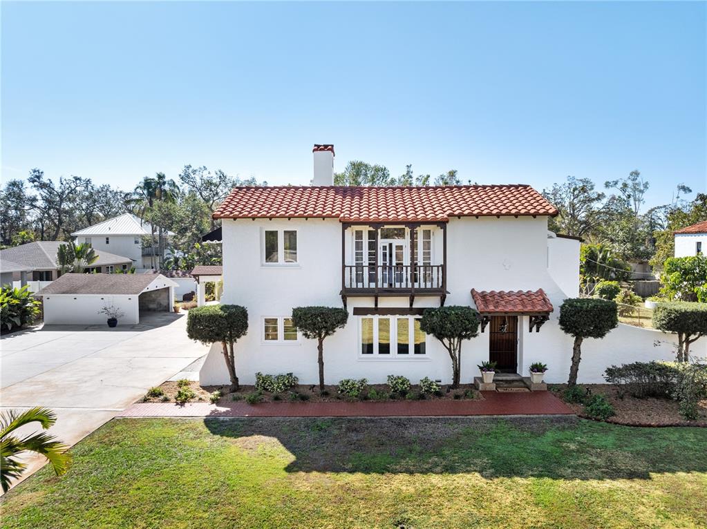 A two-story white stucco house features a red tile roof, wooden balcony, and detached garage — 6010 17TH AVENUE S, GULFPORT, FL