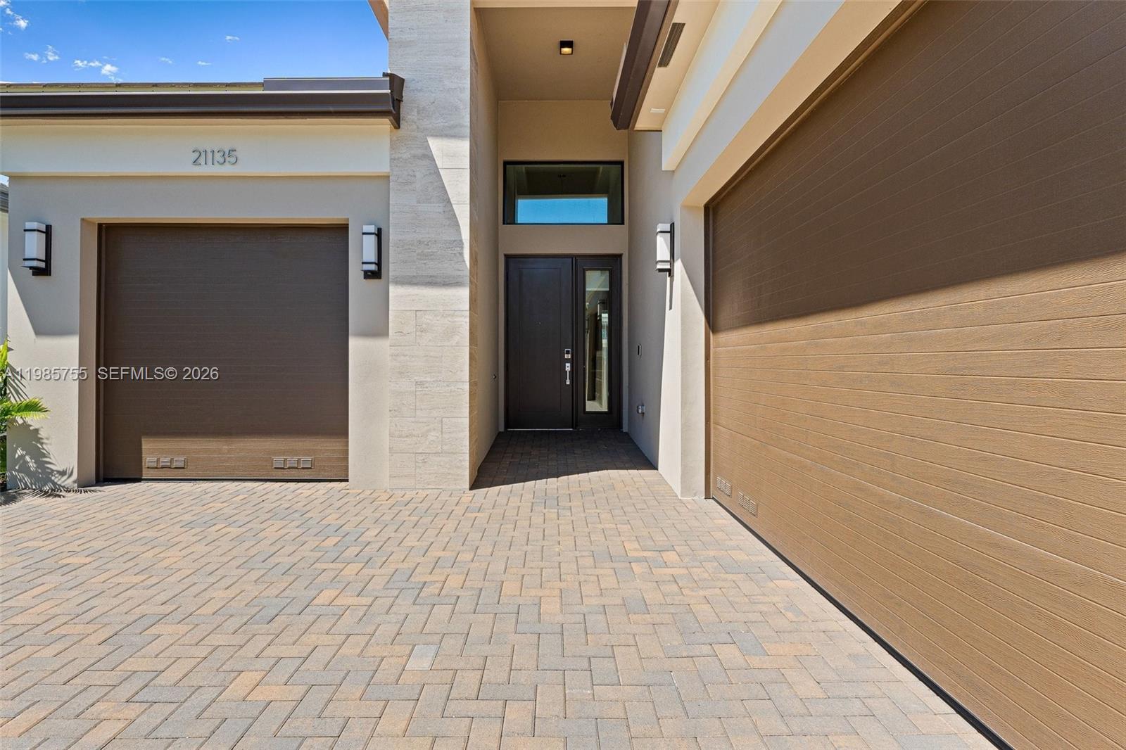 A modern house exterior features a paved driveway, two garage doors, and a front entrance — 21135 Tangelo Tree Dr, Boca Raton FL 33434, BOCA RATON, FL