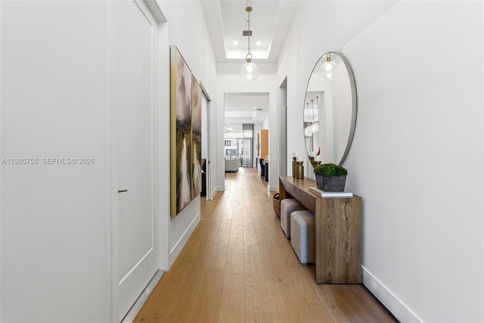 A hallway features light wood flooring, a console table with stools, and a large mirror — 21135 Tangelo Tree Dr, Boca Raton FL 33434, BOCA RATON, FL