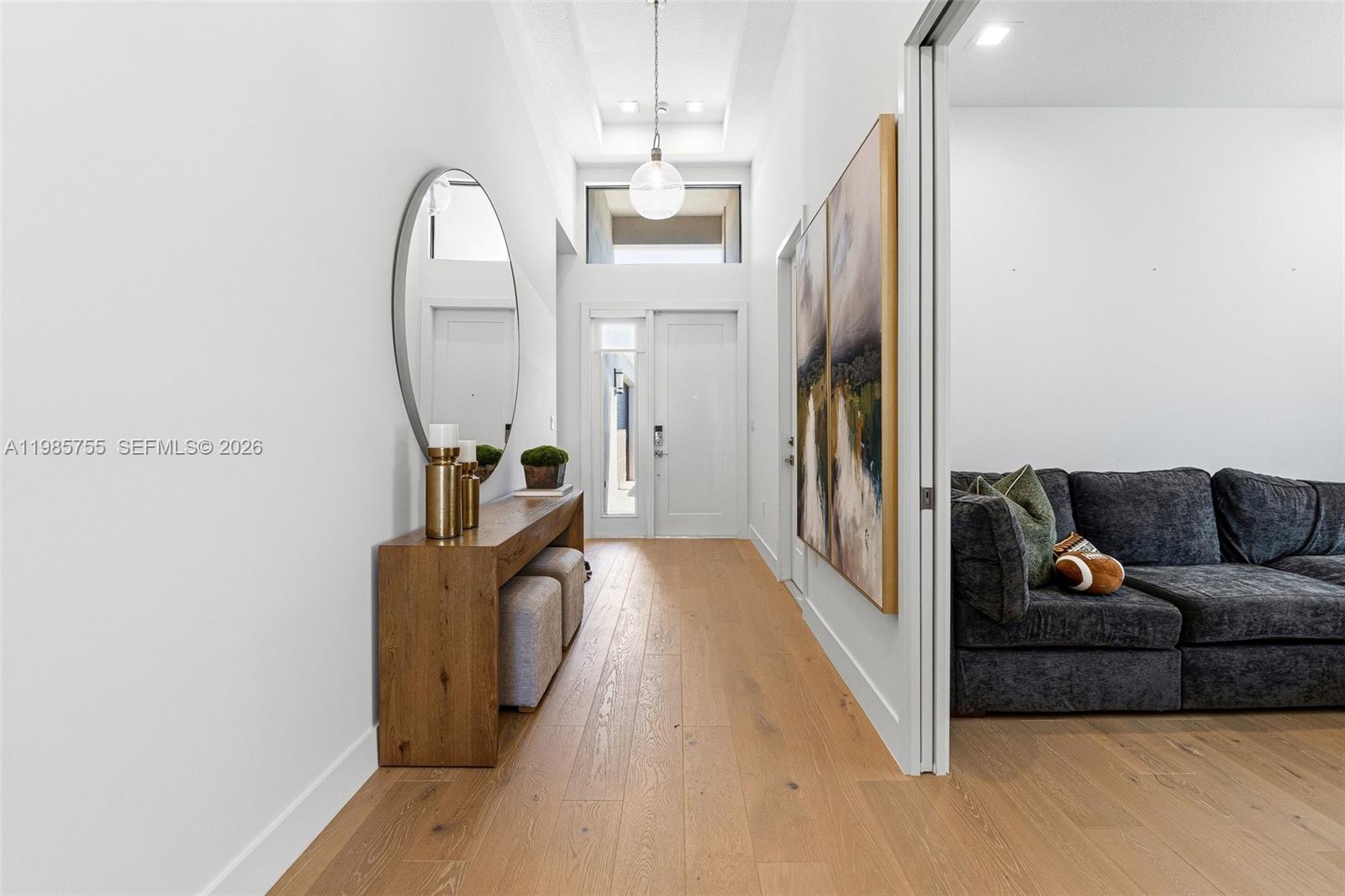 A bright entryway features light wood floors, a console table, and a large round mirror — 21135 Tangelo Tree Dr, Boca Raton FL 33434, BOCA RATON, FL