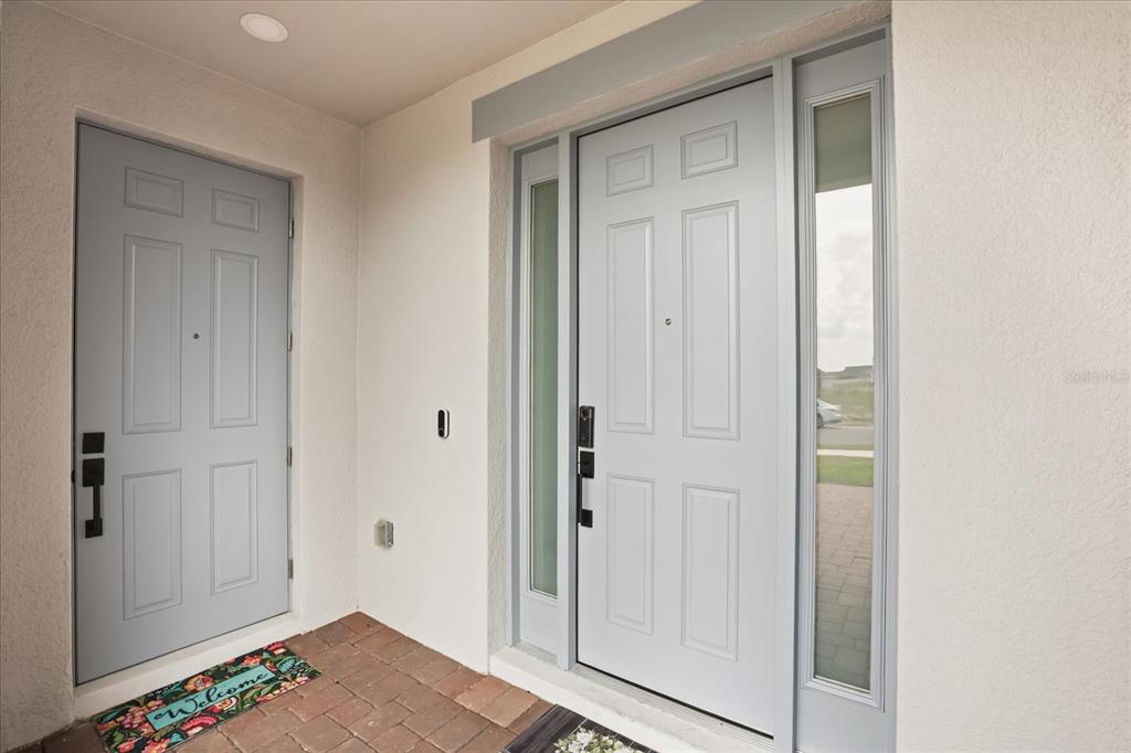 A covered entryway features two light blue doors with sidelights and a brick floor — 5867 SIERRA CROWN STREET, MOUNT DORA, FL
