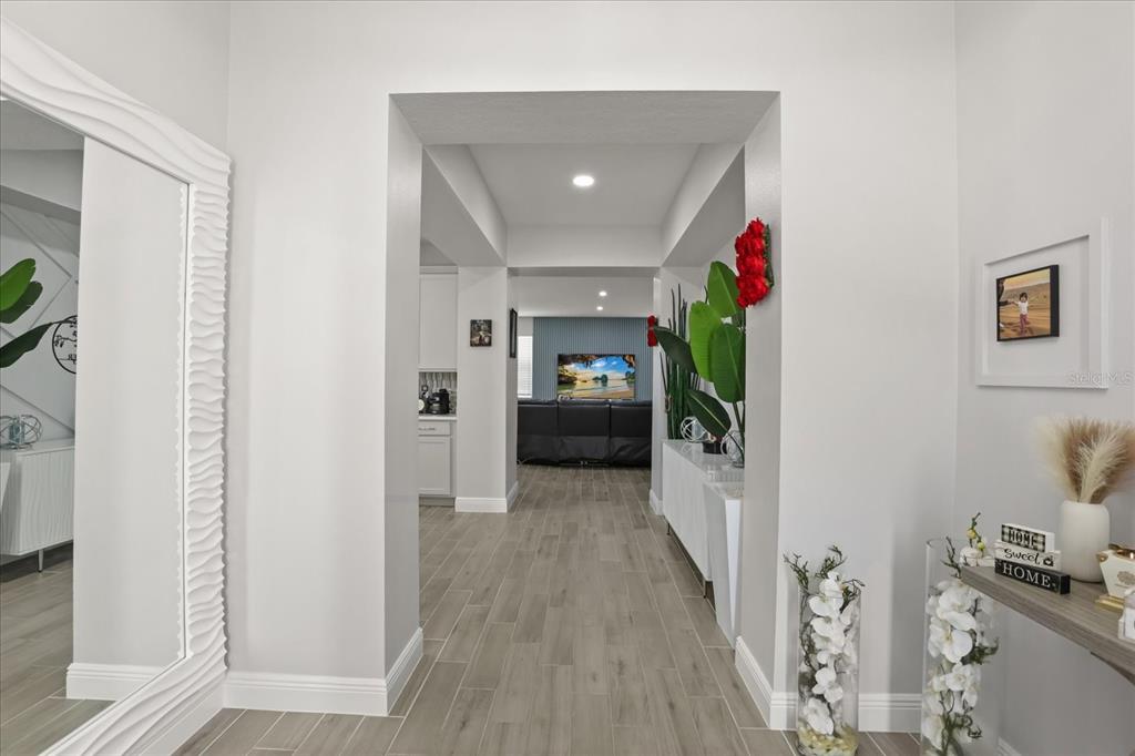 A view through a wide doorway into a living area with light wood-look tile flooring — 5867 SIERRA CROWN STREET, MOUNT DORA, FL