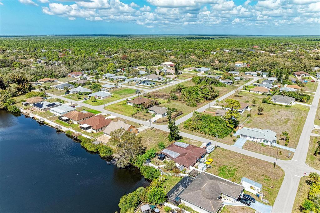 An aerial view shows a suburban neighborhood with houses situated along a canal — 12029 CORSICA LANE, NORTH PORT, FL