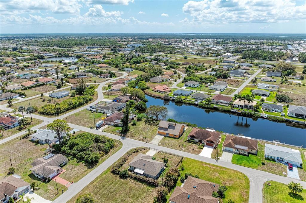 An aerial view shows a residential neighborhood with houses situated along a canal — 12029 CORSICA LANE, NORTH PORT, FL