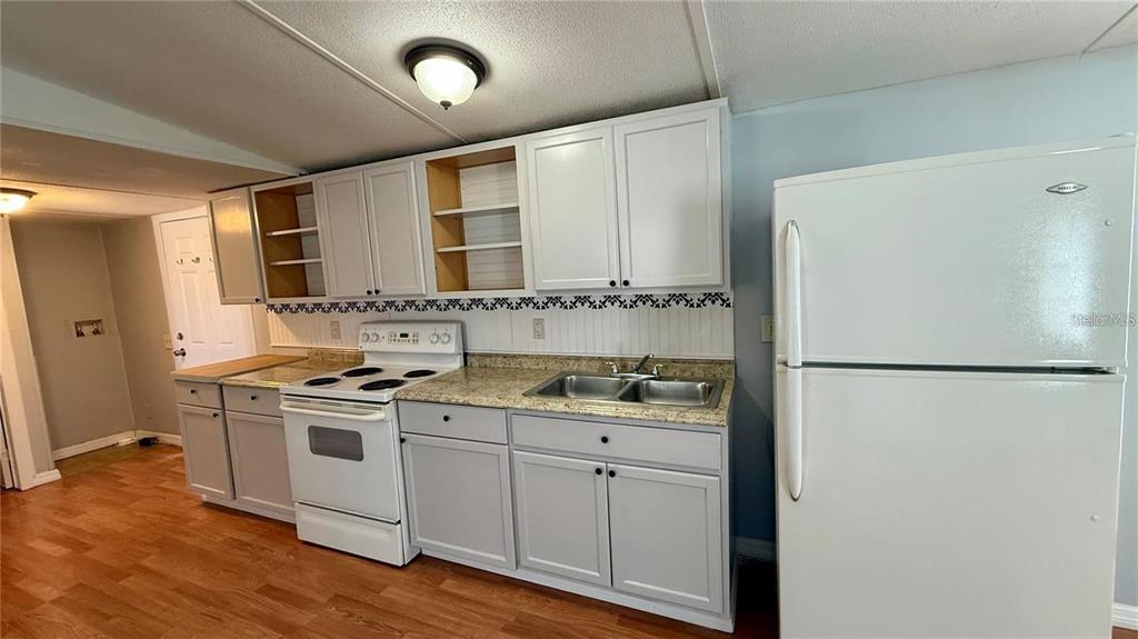 A kitchen features white cabinets, a white stove, a double sink, and a white refrigerator — 639 ELLISON PARKWAY, HAINES CITY, FL