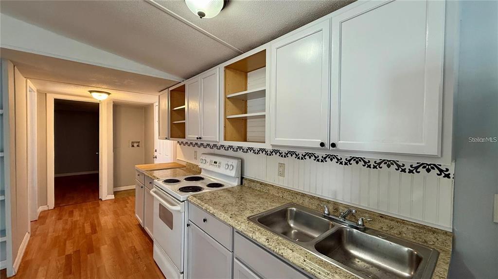 A kitchen features white cabinets, a double sink, a stove, and light-colored laminate countertops — 639 ELLISON PARKWAY, HAINES CITY, FL