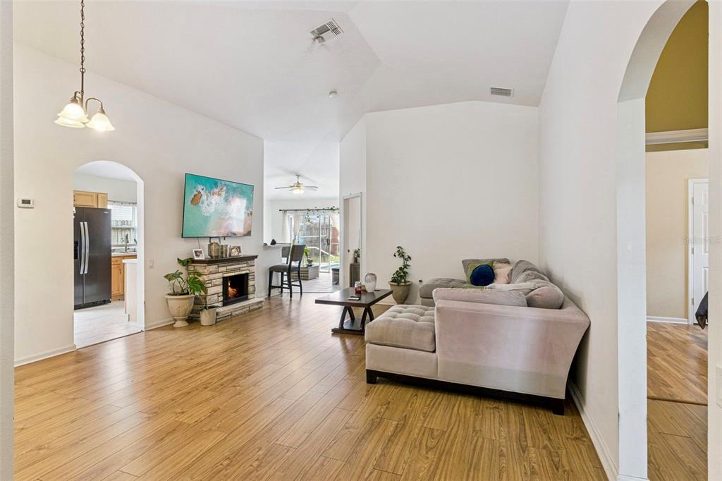 A living room with wood-look flooring, a stone fireplace, and a sectional sofa — 3195 WHOOPING CRANE RUN, KISSIMMEE, FL