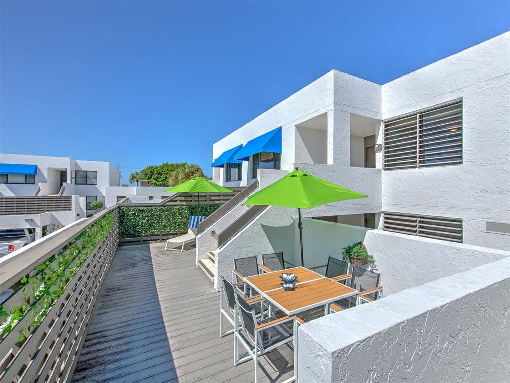 An outdoor deck features a dining set with a green umbrella and a lounge chair — 720 BAYPORT WAY UNIT 720, LONGBOAT KEY, FL