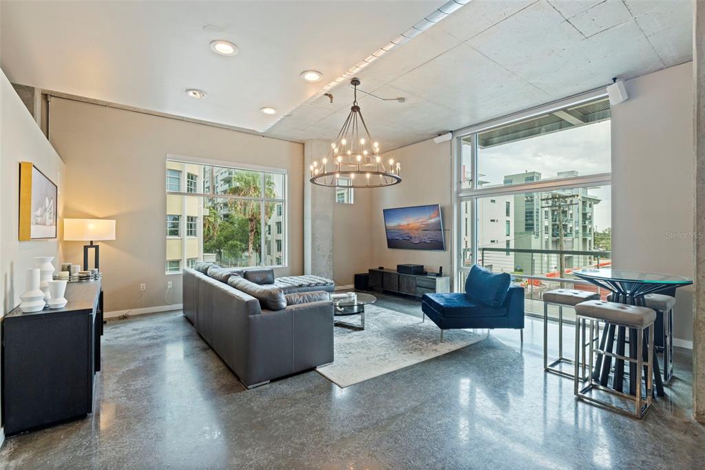 A modern living room features concrete floors, a large sectional sofa, and floor-to-ceiling windows — 101 S 12TH STREET UNIT 302, TAMPA, FL
