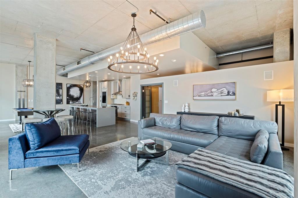 A modern open-concept living room features a concrete ceiling, industrial ductwork, and a large chandelier — 101 S 12TH STREET UNIT 302, TAMPA, FL