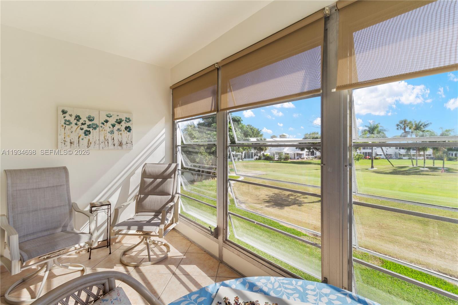A sunroom features tile flooring, jalousie windows, and a view of a golf course — 2850 W Golf Blvd # 211, Pompano Beach FL 33064, POMPANO BEACH, FL